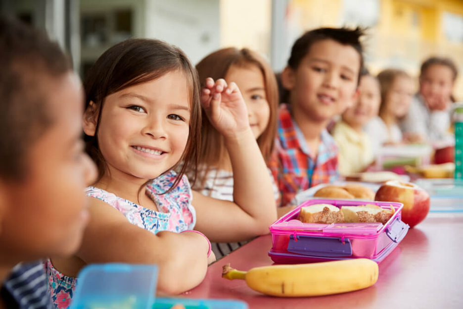 School lunch table with girl smiling at the camera
