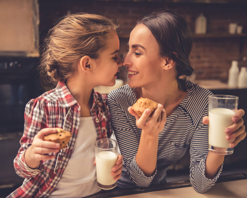 Mom and daughter enjoying muffins and a glass of milk