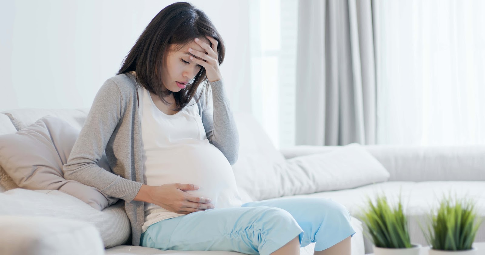Pregnant woman holding her head in misery