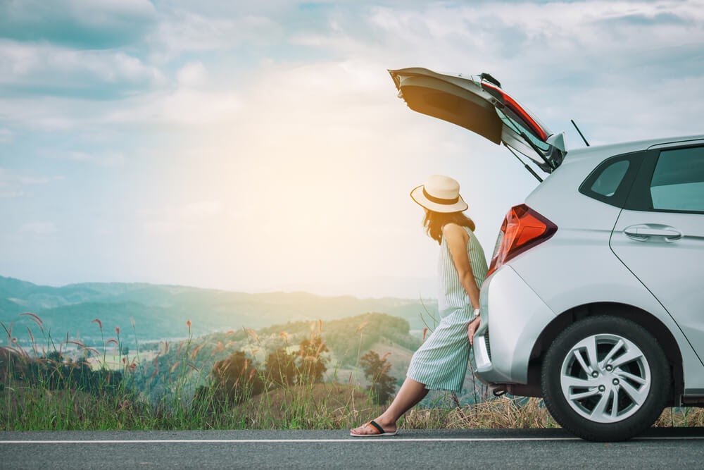 Woman looking at the scenery from the back of her car