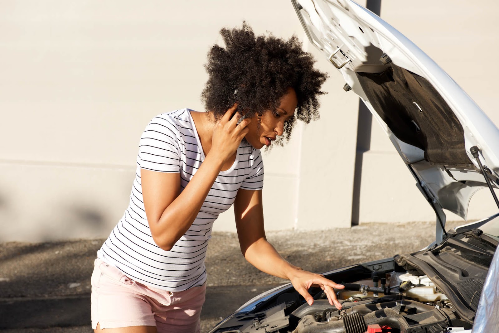 Woman on the side of the road looking at her engine