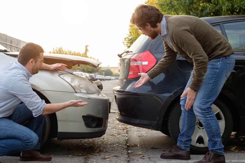 Two men looking at their cars after a rear-end accident