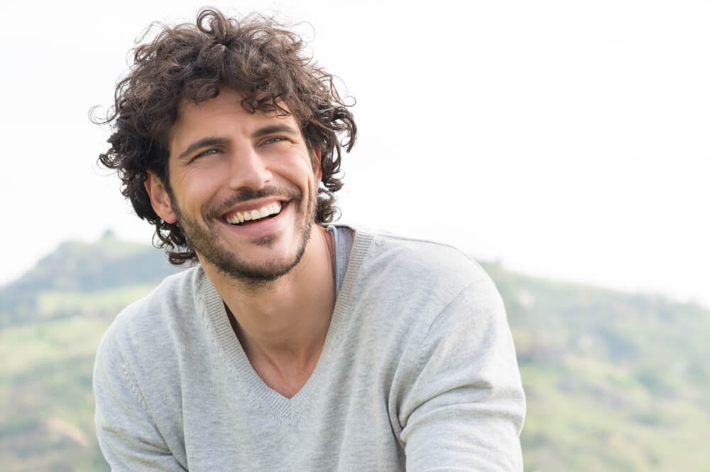 Man smiling with a hill in the background