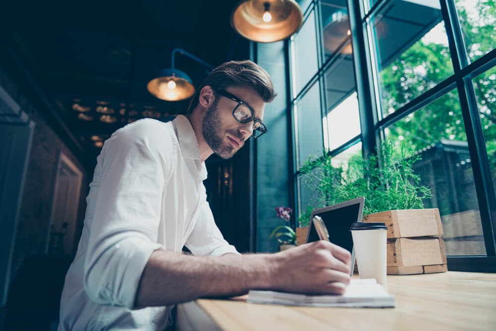 Man writing in a notebook at a coffee shop