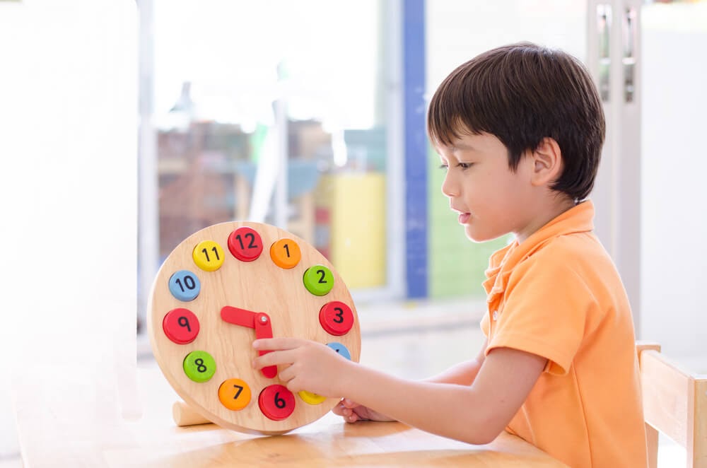 Young boy playing with wooden clock