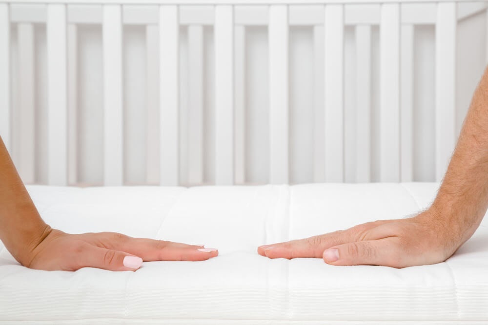 Two hands pressing on a mattress
