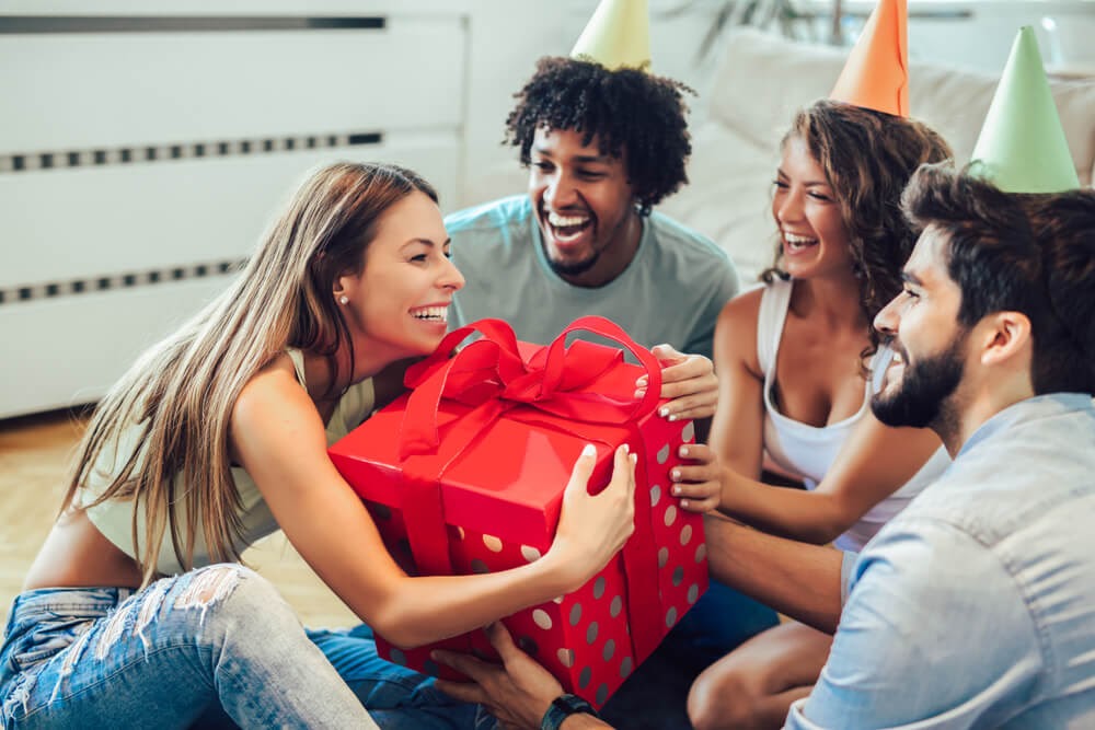 Friends watching woman open gifts