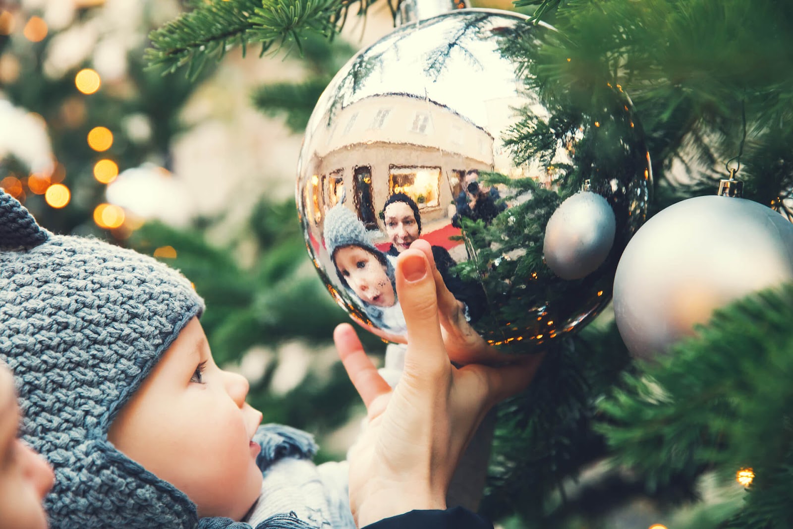Baby looking at giant ornament on Christmas tree