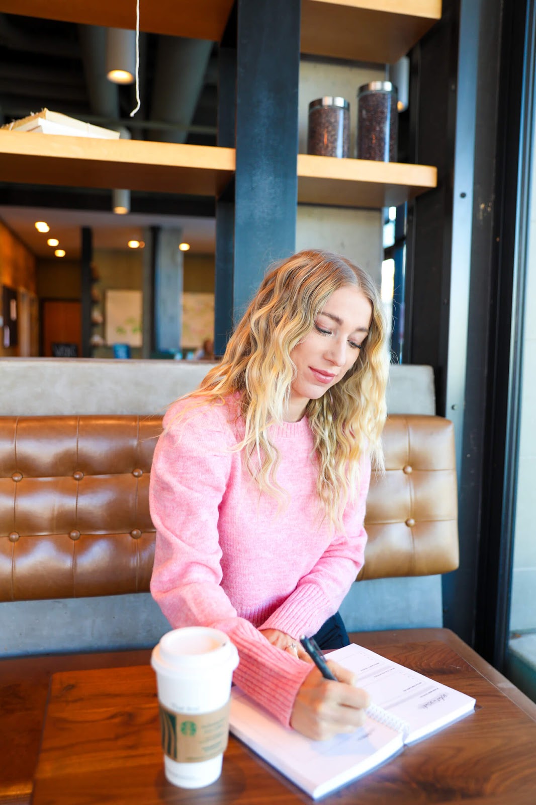 Person writing in a journal in coffee shop