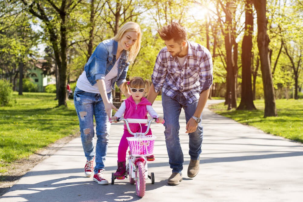 Parents teaching daughter to ride a bike in a pk