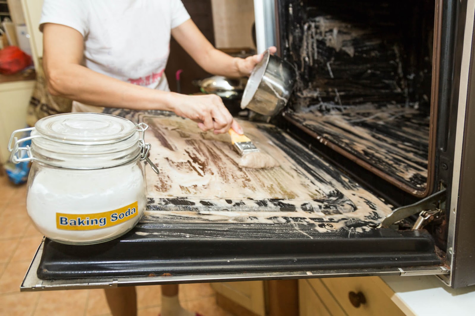 Woman scrubbing baking soda on her oven