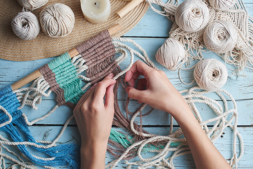 Person weaving a wall tapestry