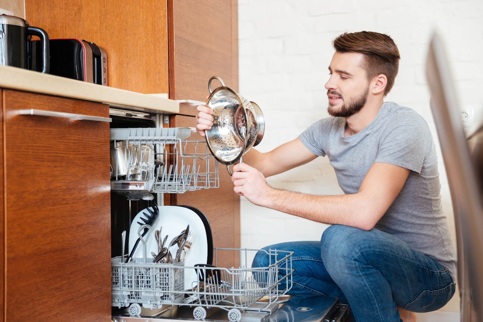 Man looking at dishes in his dishwasher
