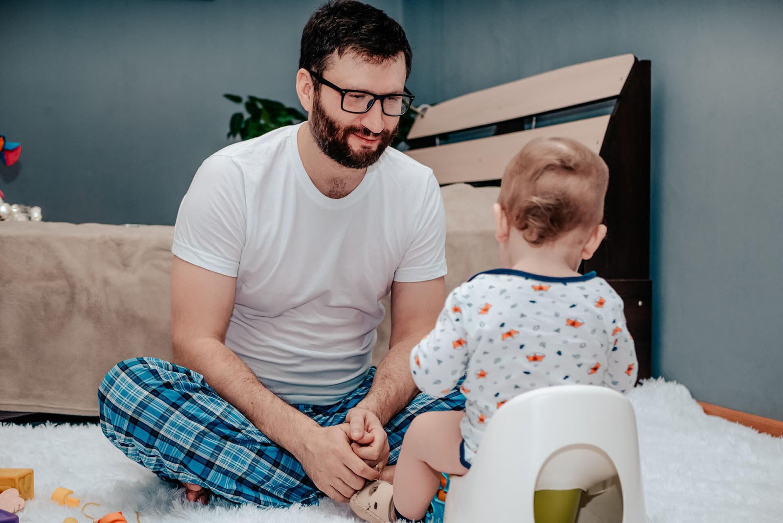 Father talking to toddler with son on a potty chair