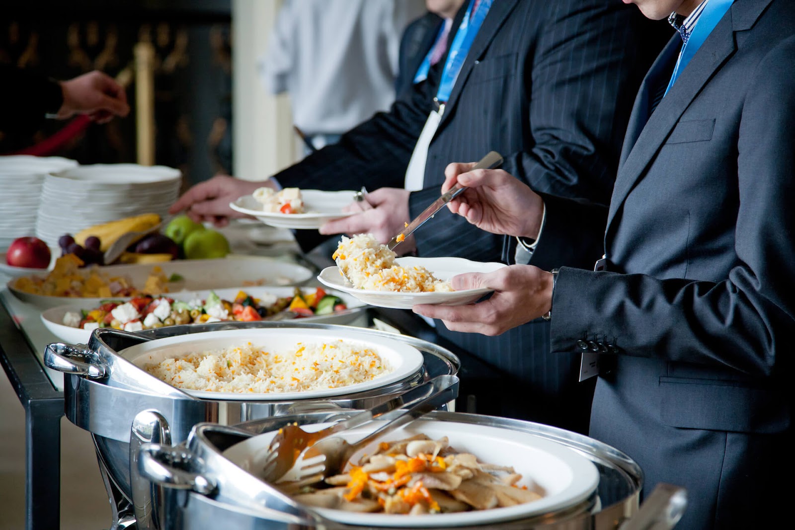 Men in suits moving through a buffet