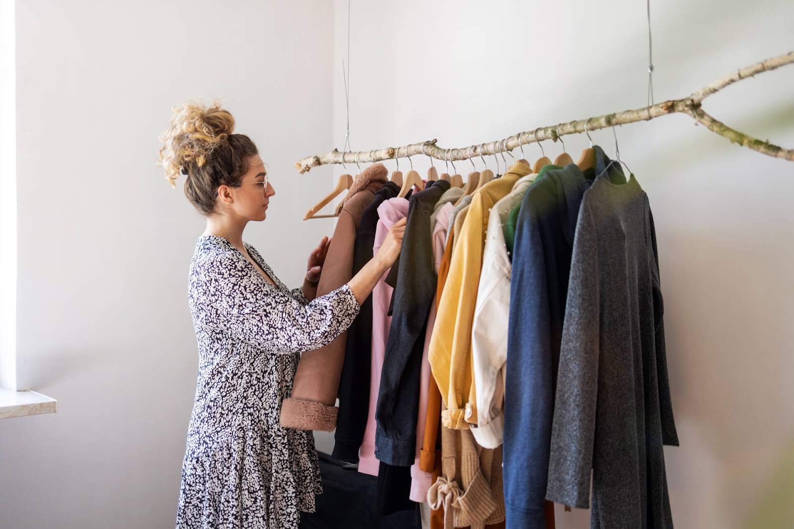 Woman picking clothes from her hip, tree branch clothing rack