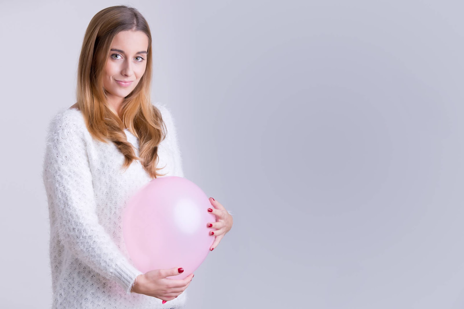 Woman holding balloon up to her belly