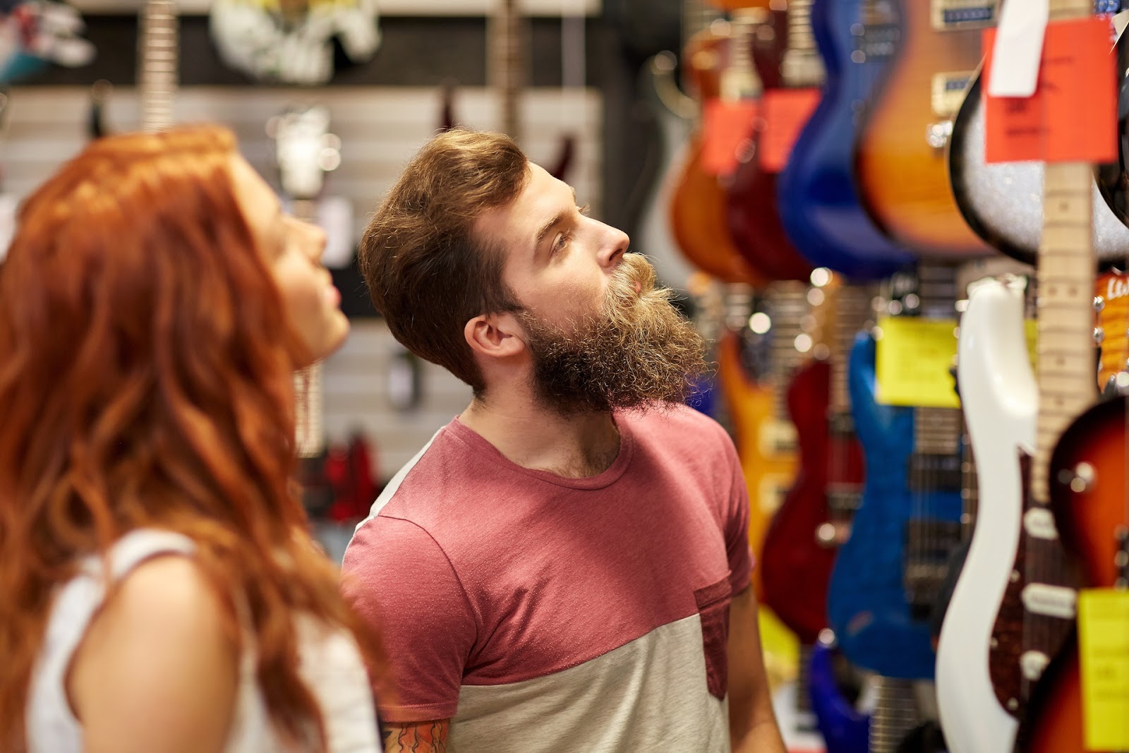 Bearded man and woman looking at guitars in the store