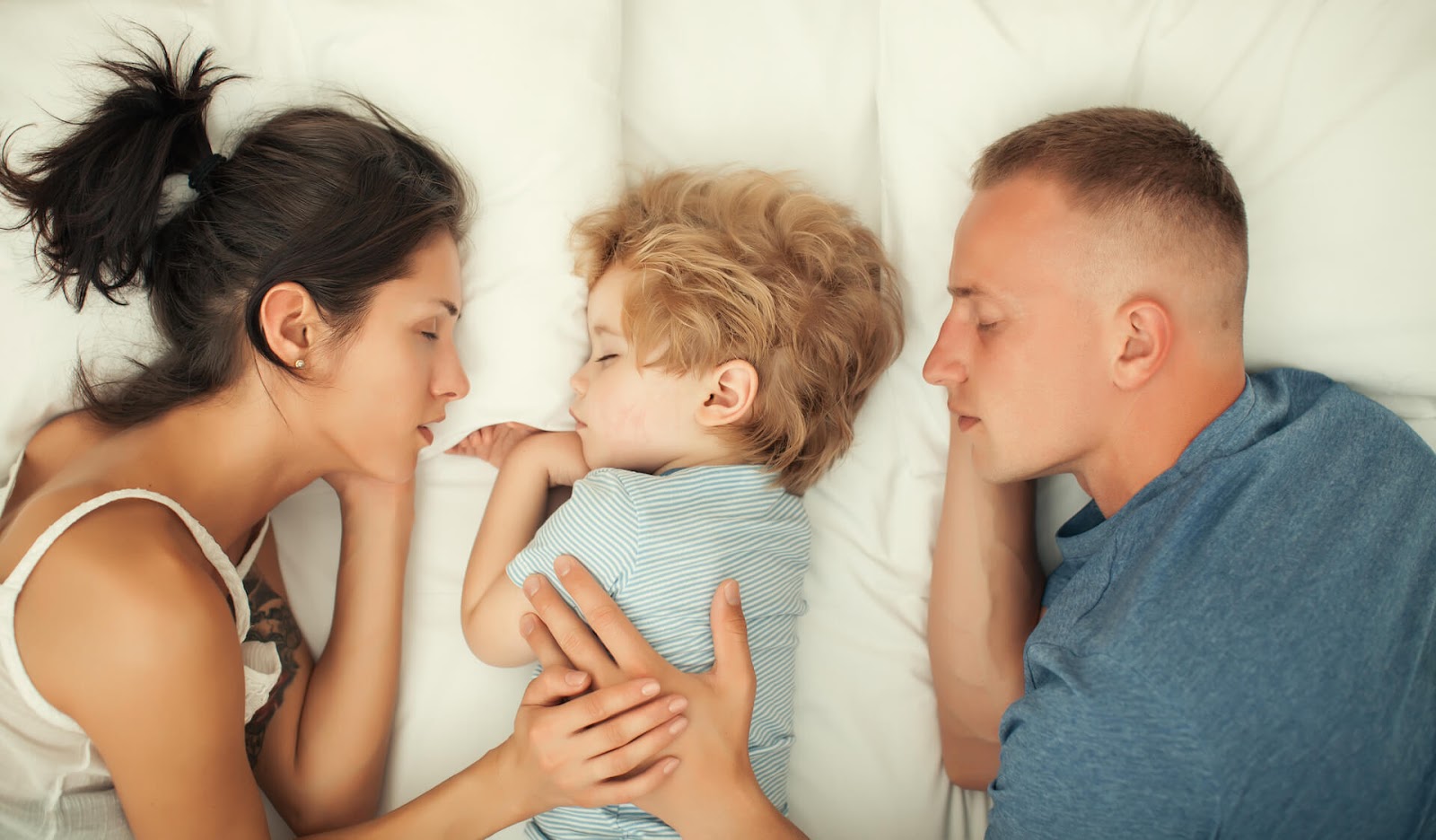Child sleeping in bed between parents