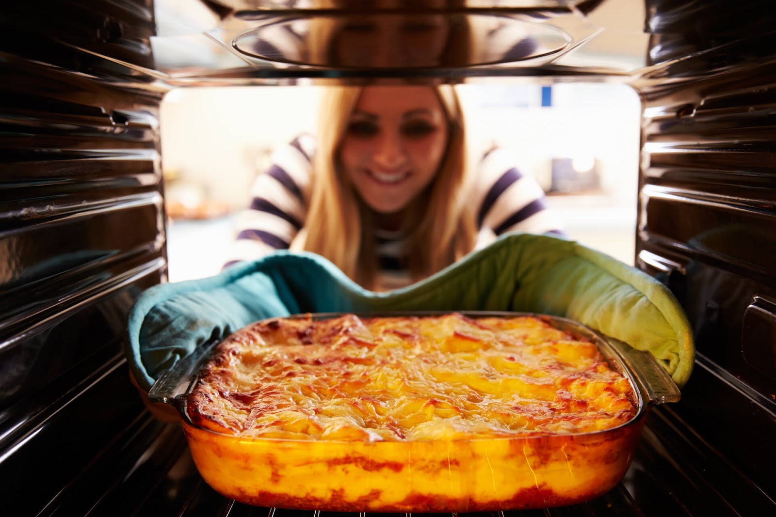 Woman pulling casserole from oven