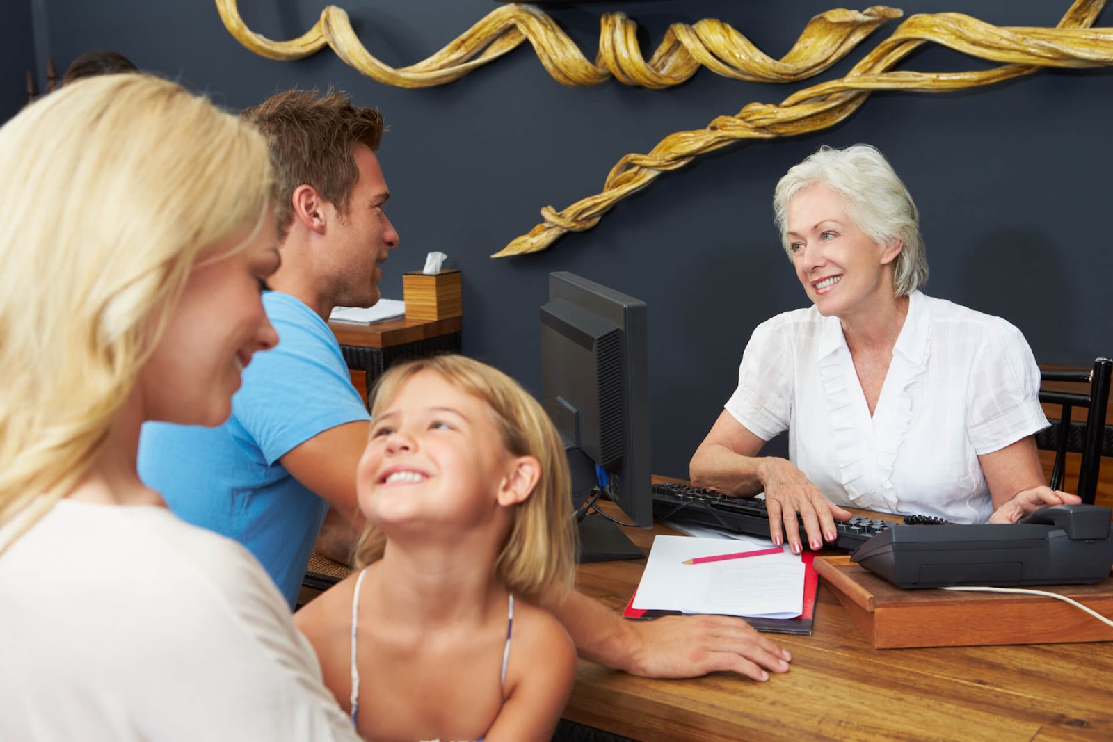 Family talking with a lady at the desk in a friendly manner
