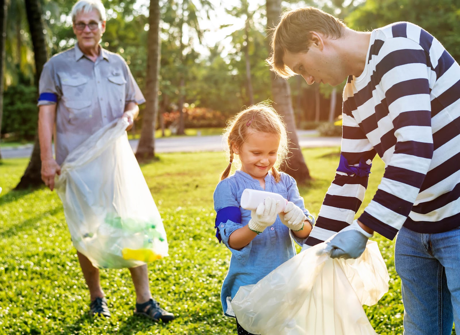 Man helping his daughter pick up trash in the park