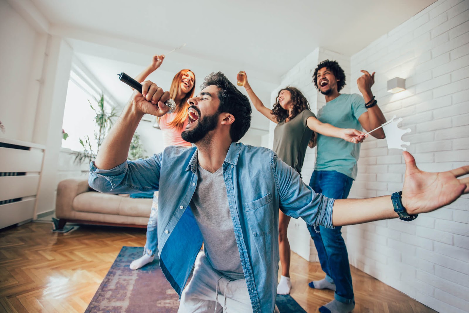 Man singing karaoke with his friends dancing in the background