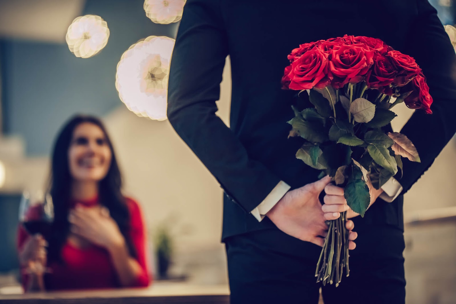 Man surprising a woman with red roses