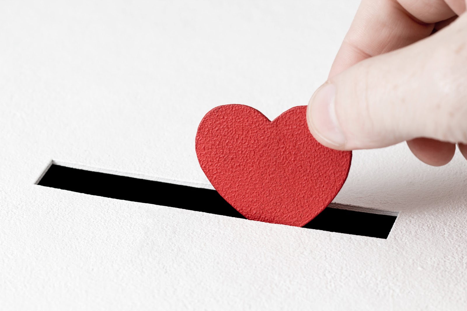Hand putting a red heart in a box