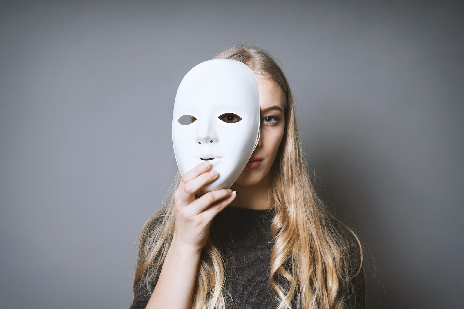 Woman hiding behind a mask