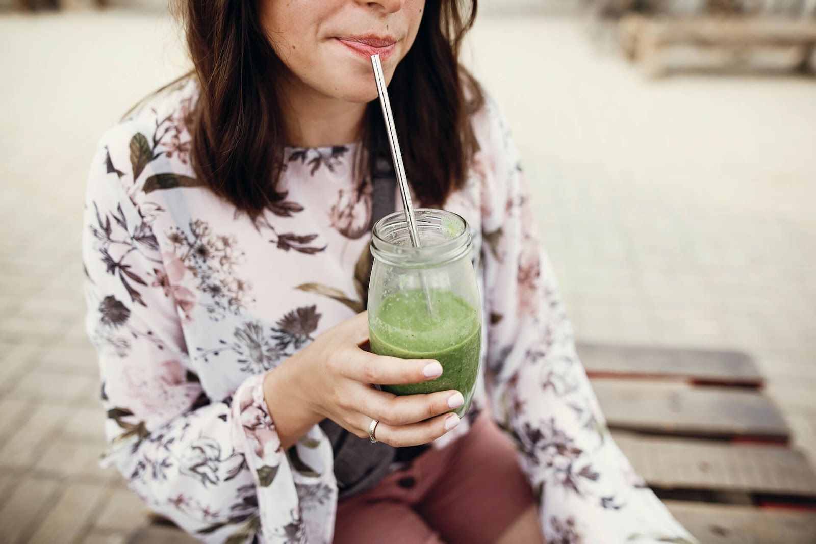 Woman drinking a green smoothie with a metal straw