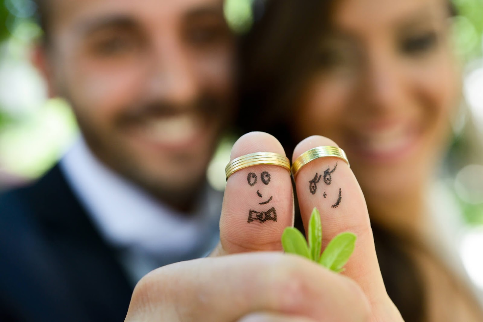 Bride and groom with rings on their thumbs & a face drawn on