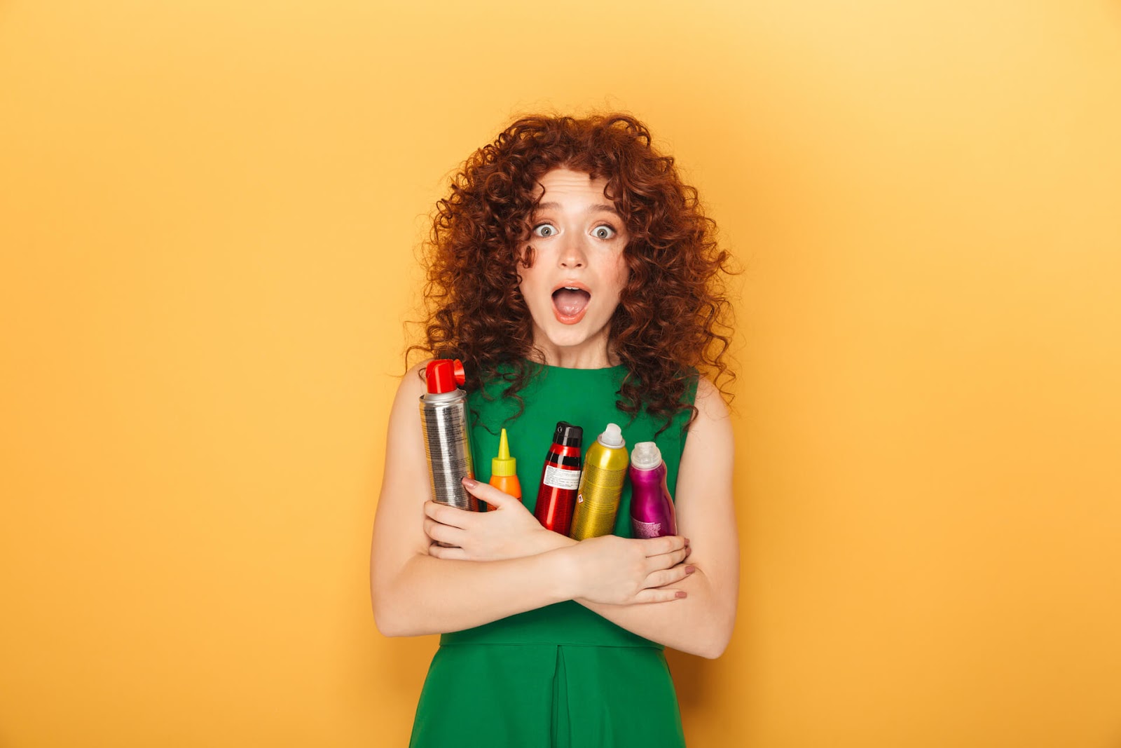 Curly-haired woman holding onto her hair products that aren't curly girl method approved