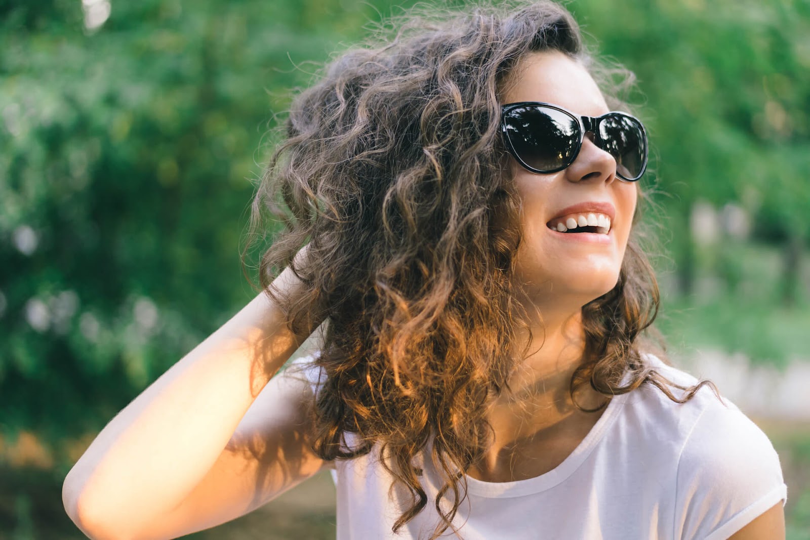 Curly-haired woman smiling in the sun