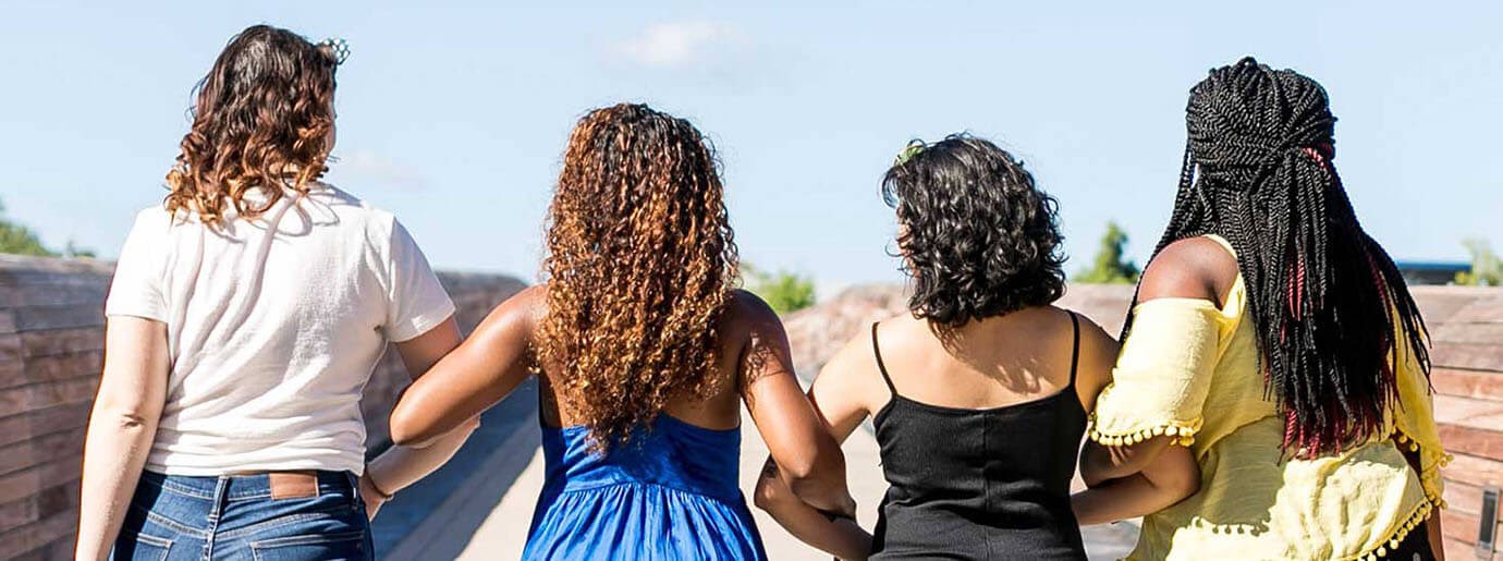Curly-haired women walking arm in arm