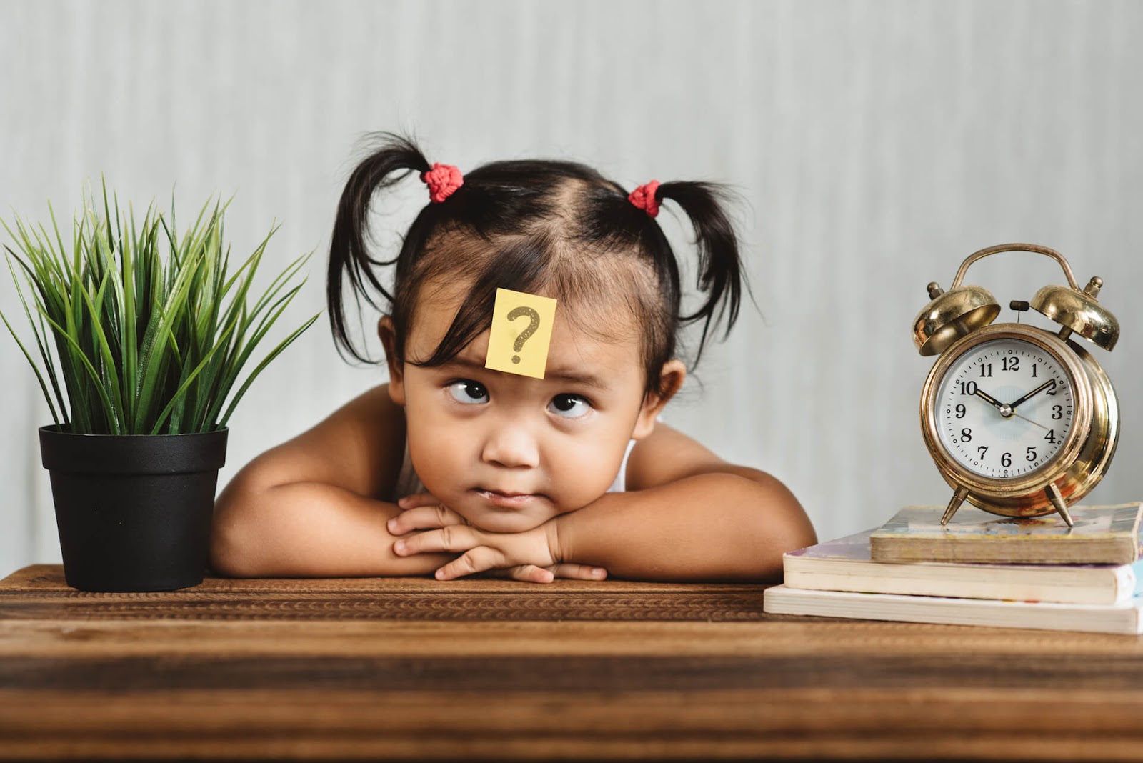 Young girl with a question mark stuck to her forehead
