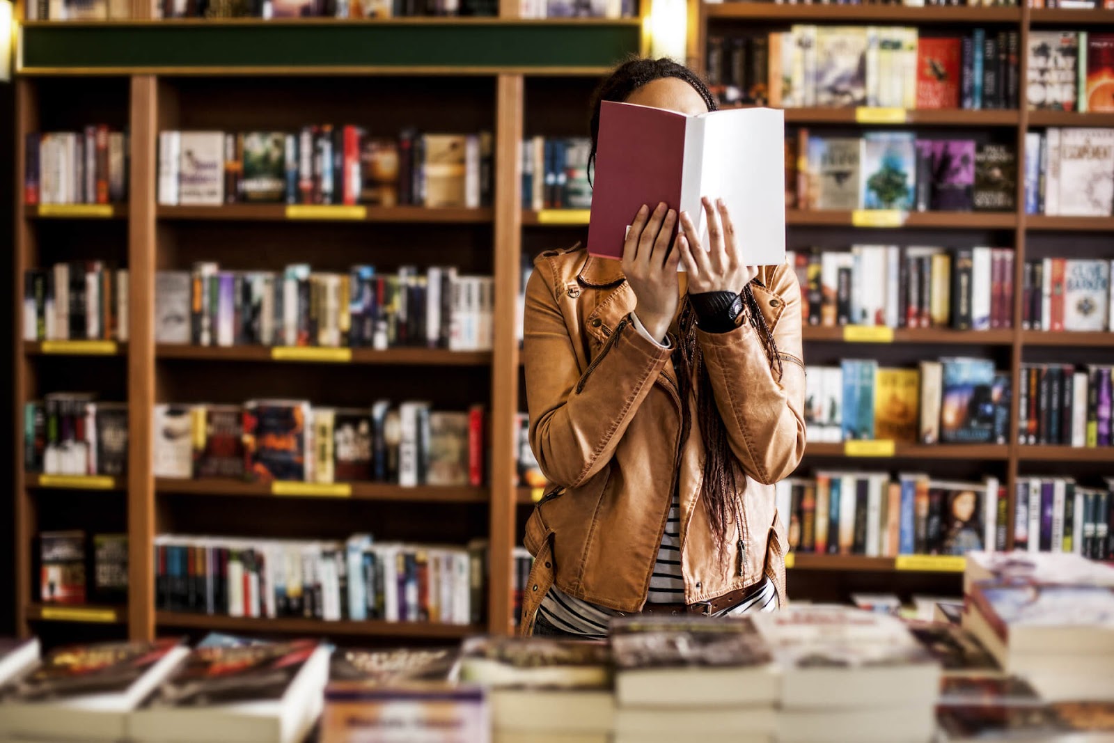 Woman holding a book in front of her face in a bookstore