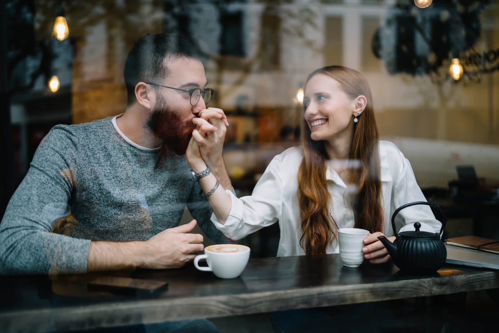 Man kissing woman's hand in a coffee shop