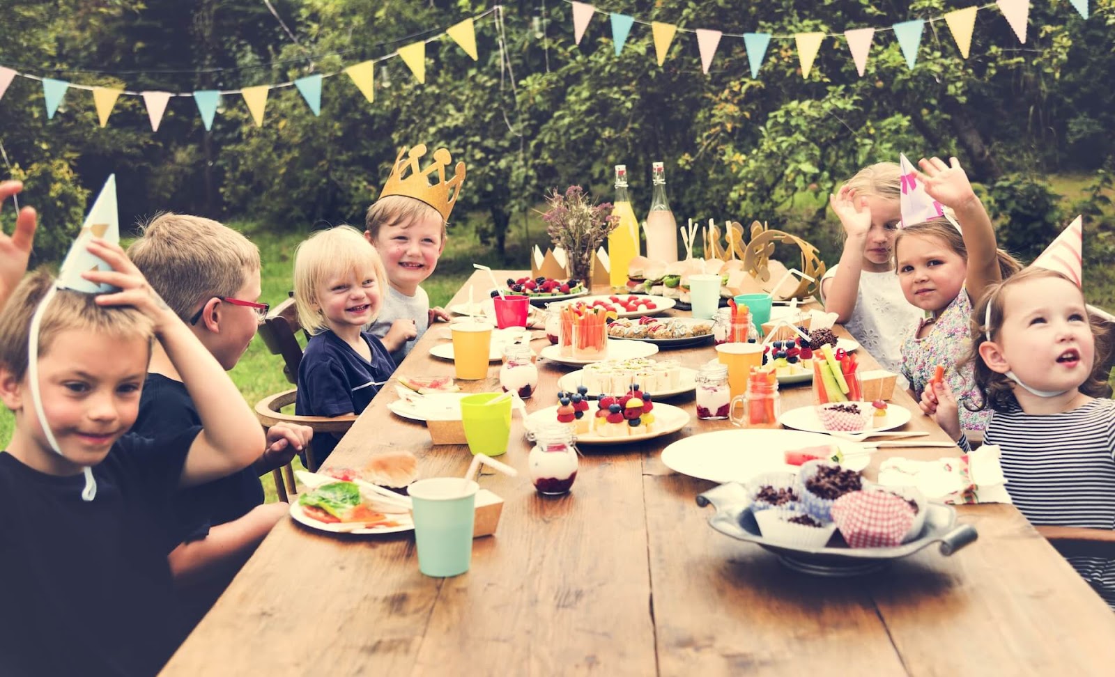 Kids sitting around a table at a backyard birthday
