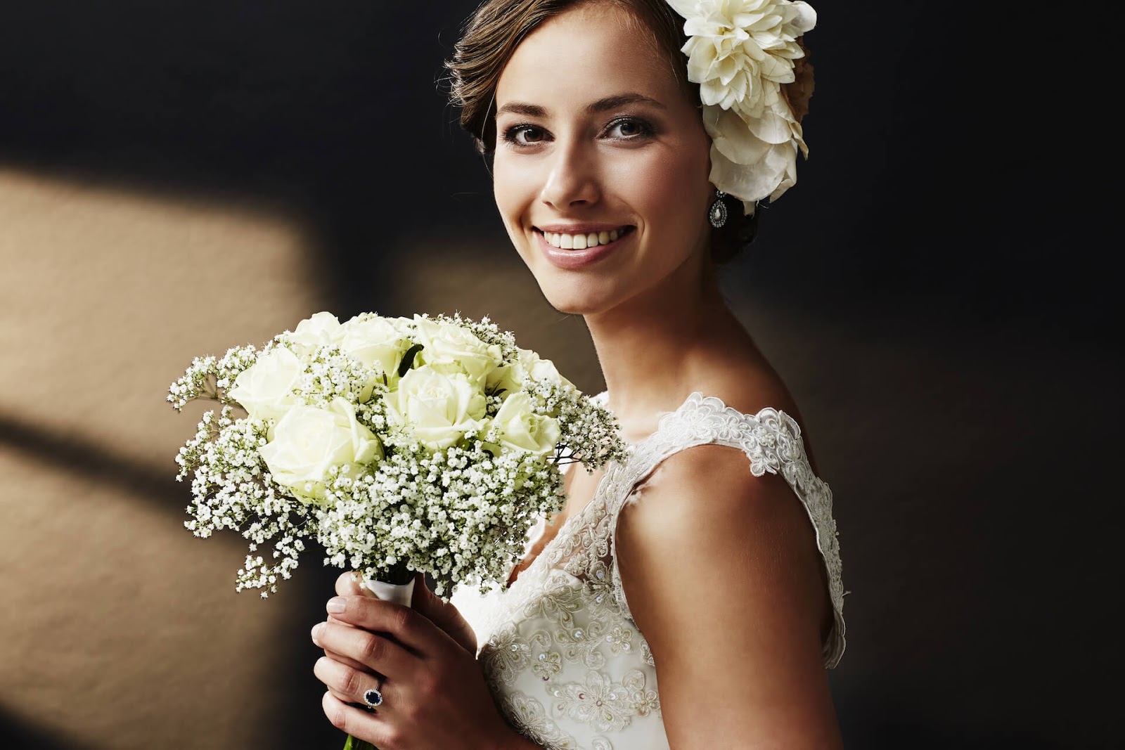 Smiling bride looking at the camera with tear drop earrings and a floral headiece