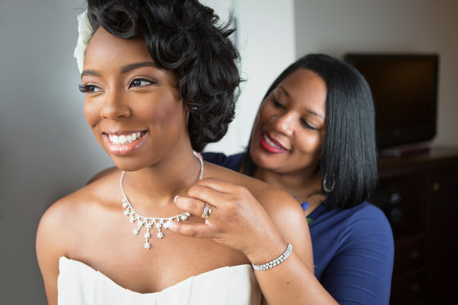 Mother putting necklace on her bride daughter
