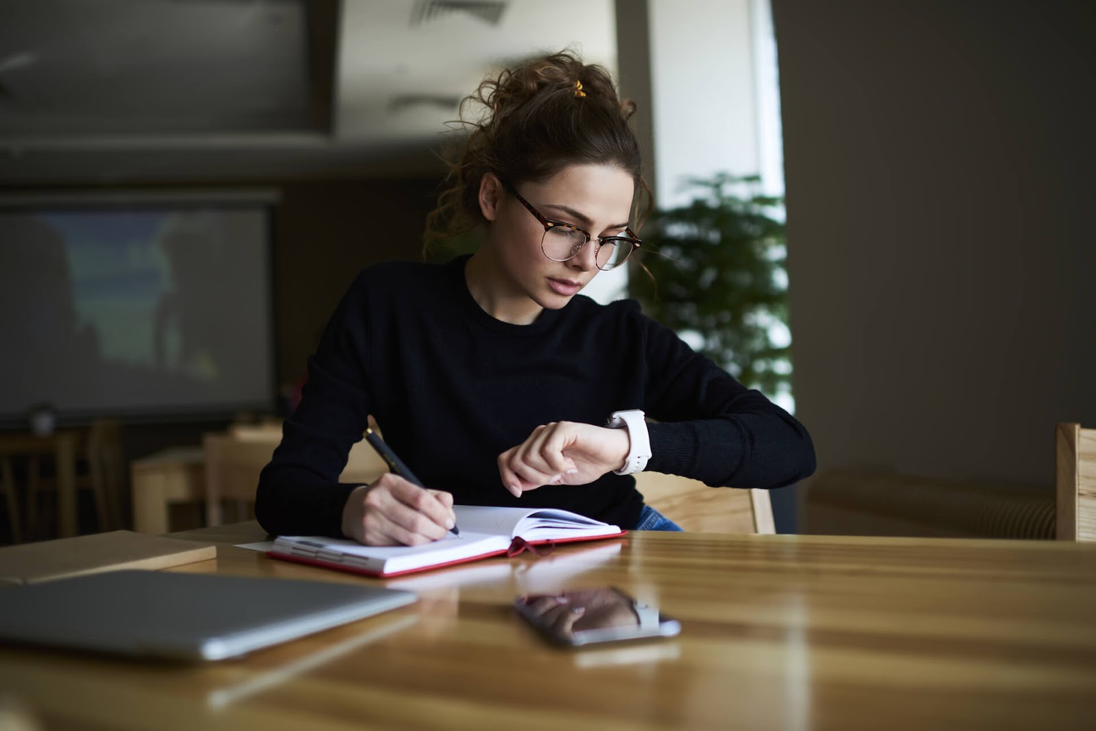 Woman looking at her watch while she journals