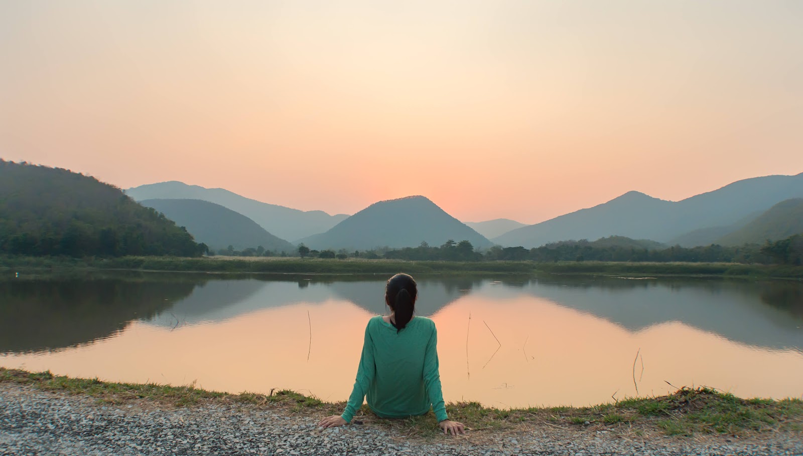 Woman enjoying a serene lake and mountain scene