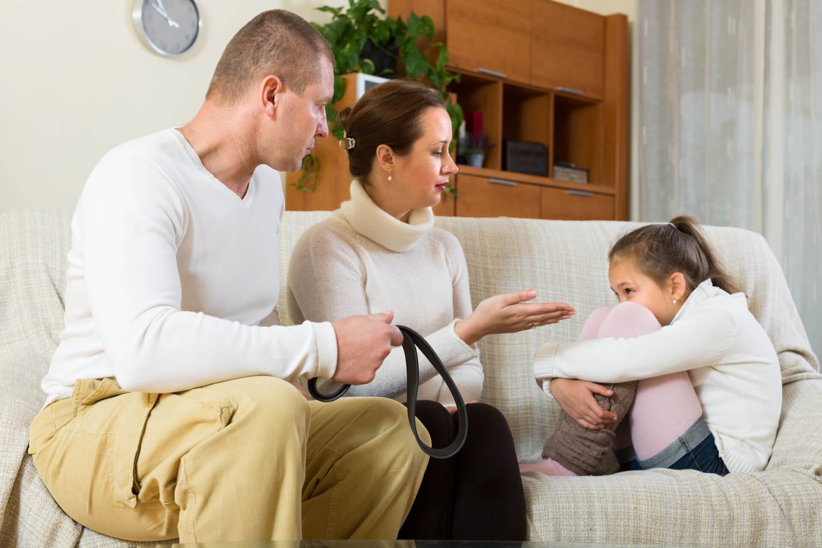 Parents lecturing their daughter on the couch