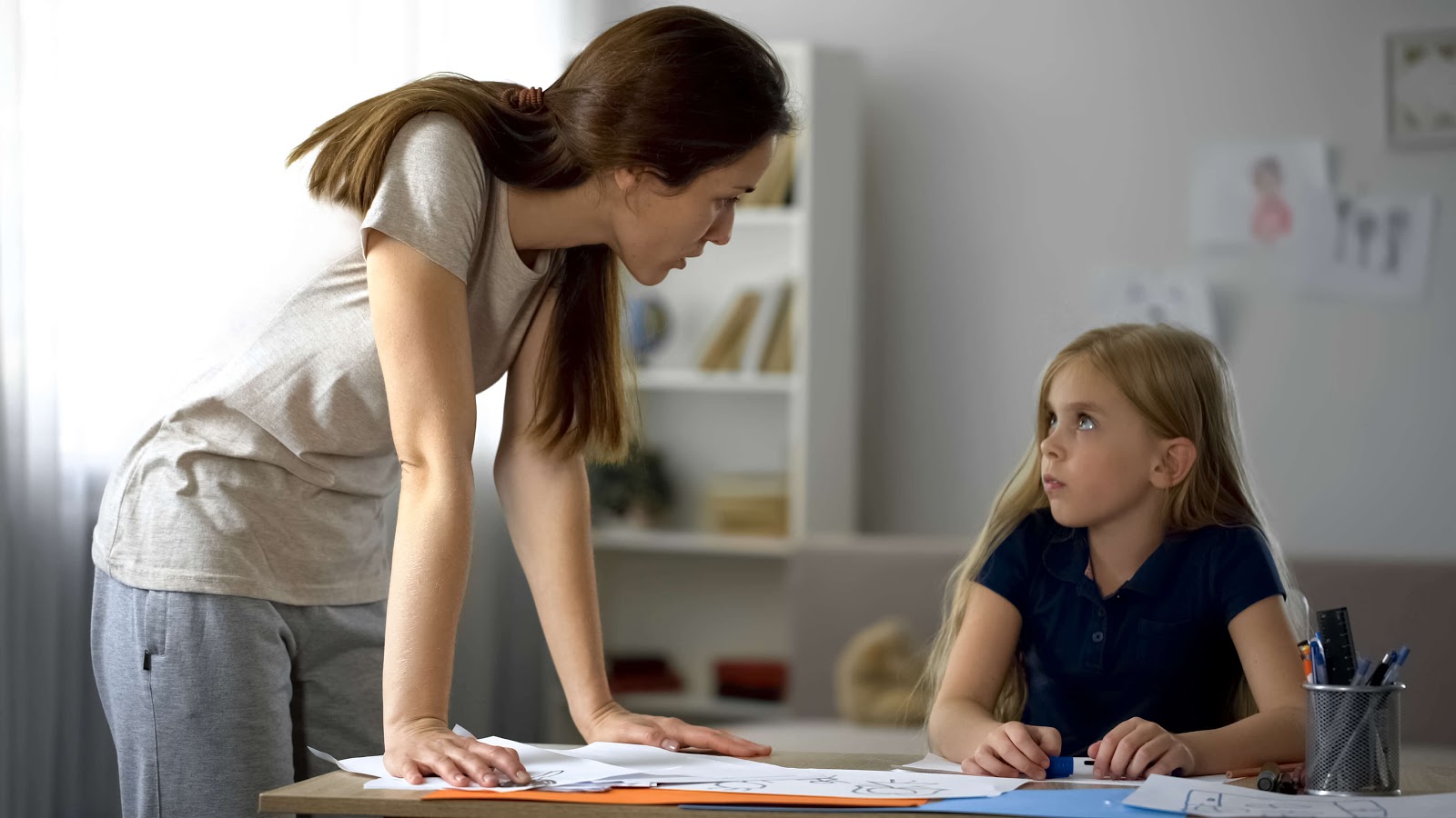 Mom hovering over daughter with disappointment in her eyes