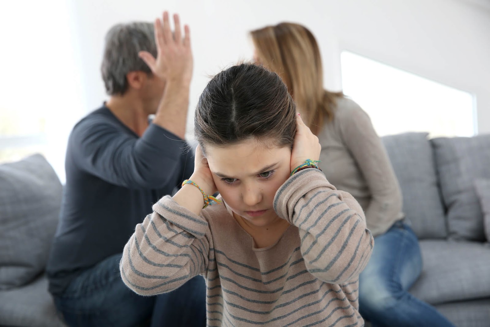 Child covering her ears as her parents fight