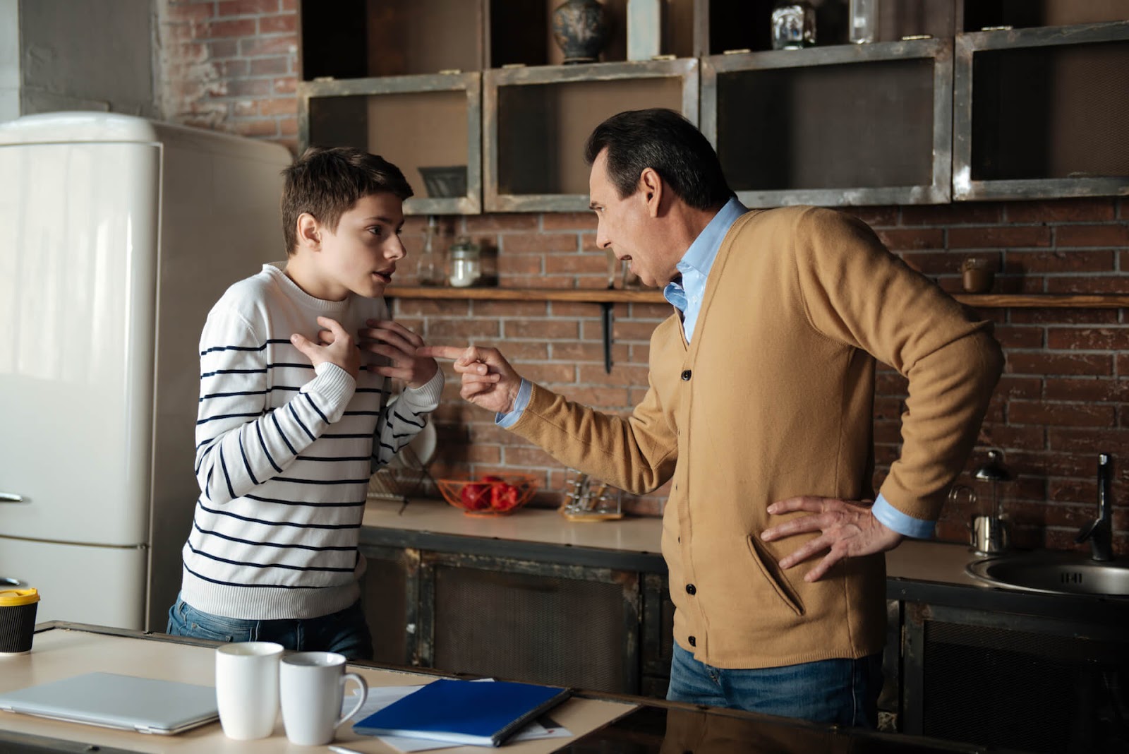 Father yelling and pointing his finger at his teenage son