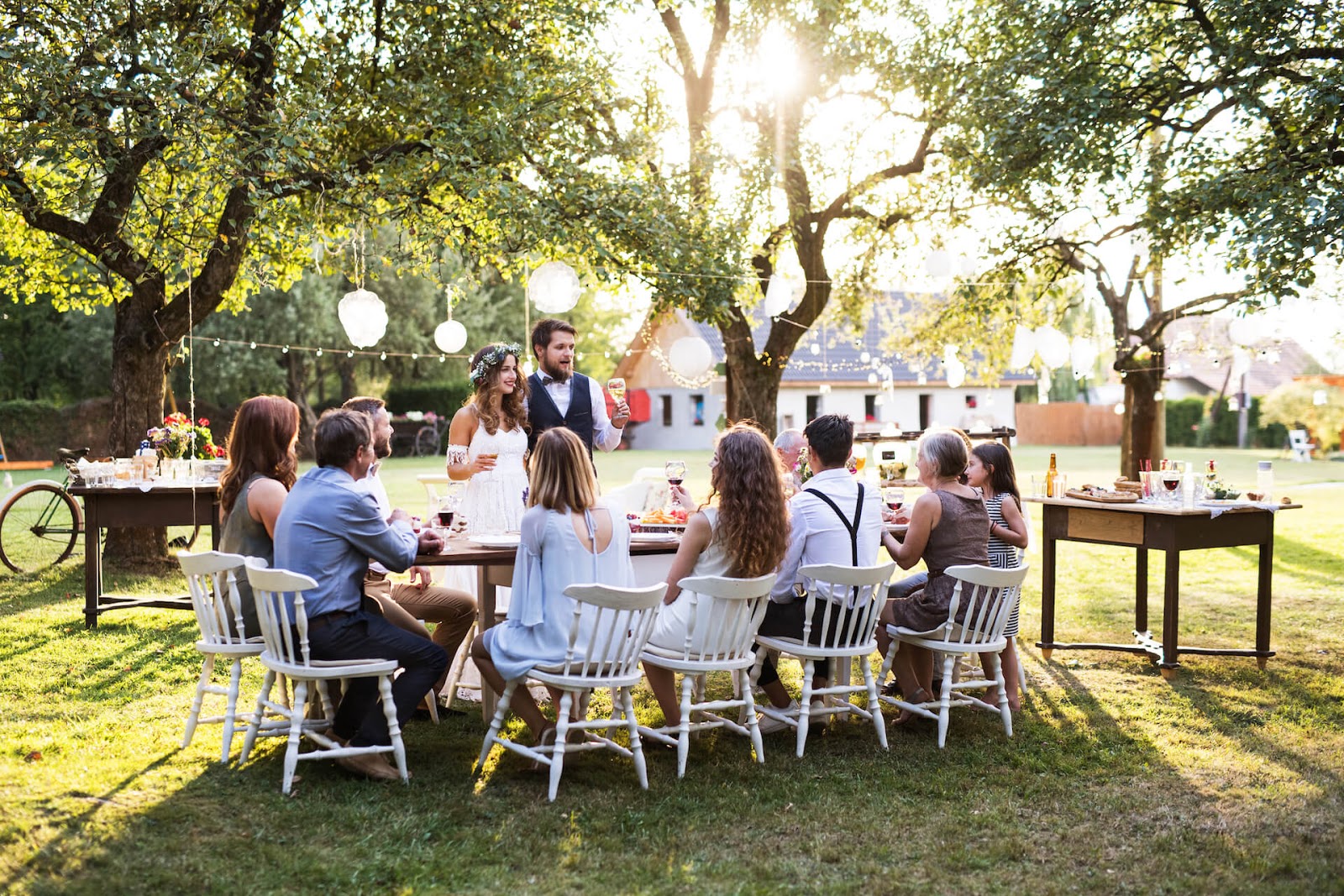 Bride and groom in a beautiful outdoor wedding around the table with their guests