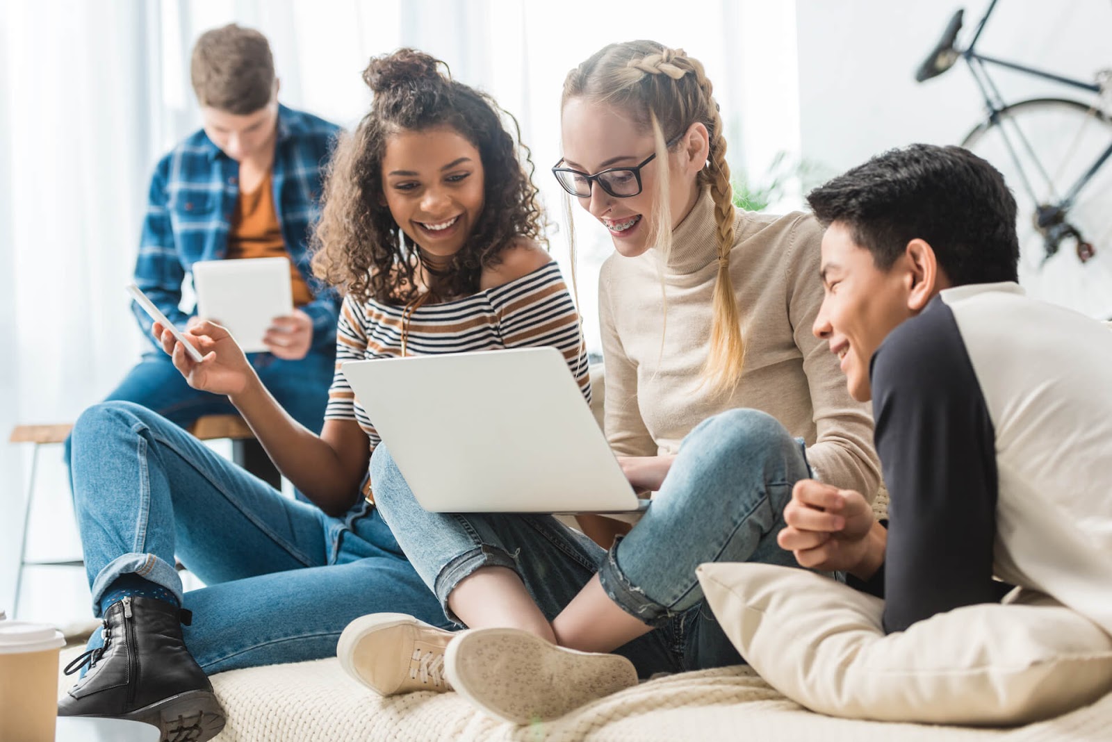 Teenagers hanging out and looking at a laptop together