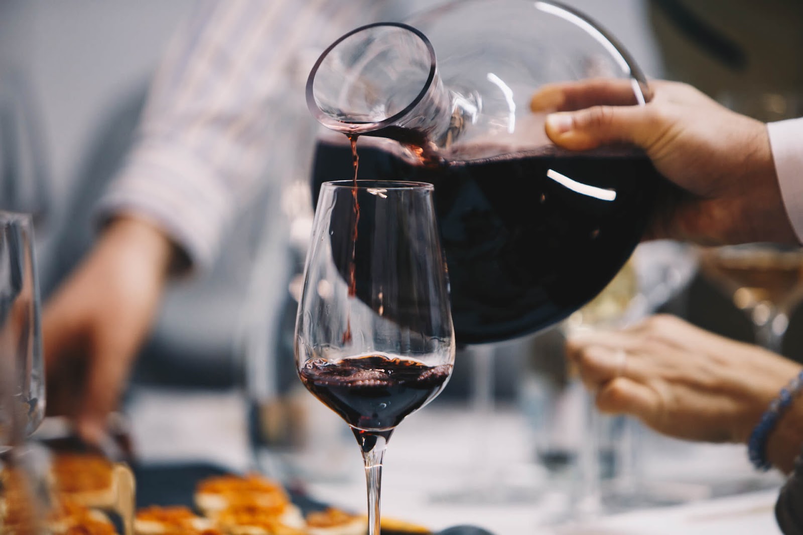 Someone pouring wine from a decanter into a wine glass